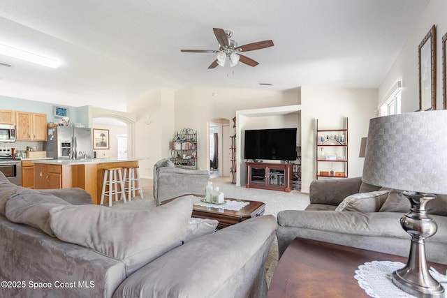 living area with light carpet, arched walkways, visible vents, lofted ceiling, and a ceiling fan