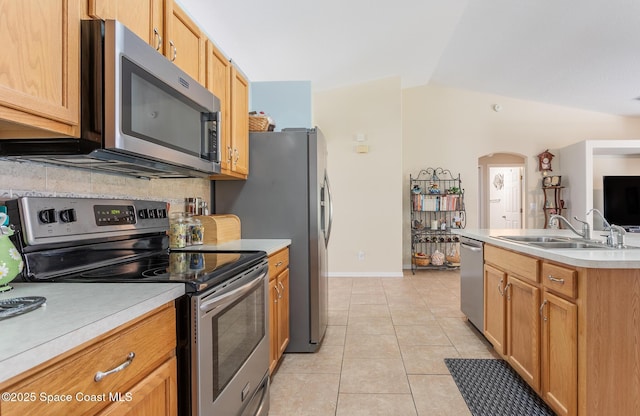 kitchen featuring backsplash, light countertops, light tile patterned floors, a sink, and appliances with stainless steel finishes