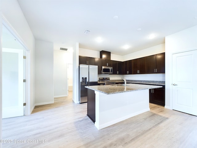 kitchen with sink, stainless steel appliances, light stone counters, light hardwood / wood-style floors, and dark brown cabinetry