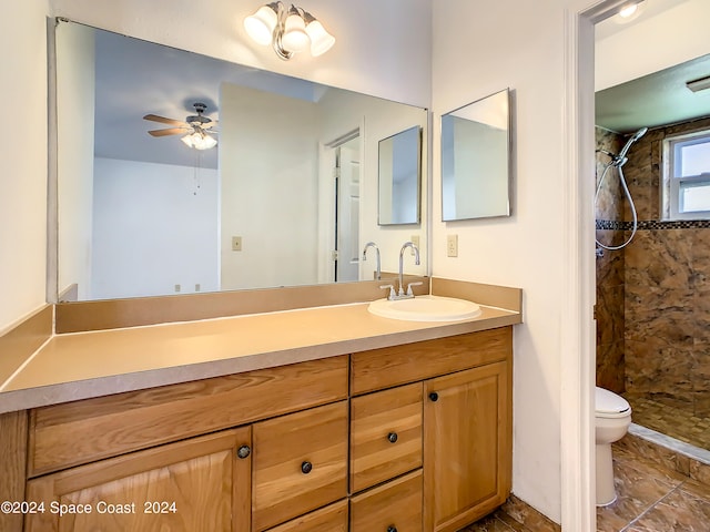 bathroom with ceiling fan, toilet, vanity, tile patterned floors, and tiled shower