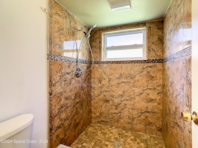 bathroom with toilet and a tile shower