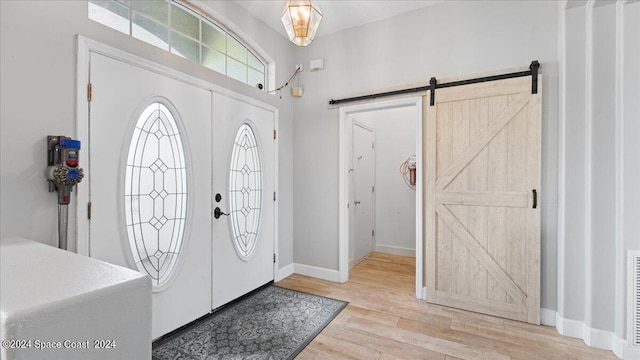 foyer entrance with light wood-type flooring and a barn door