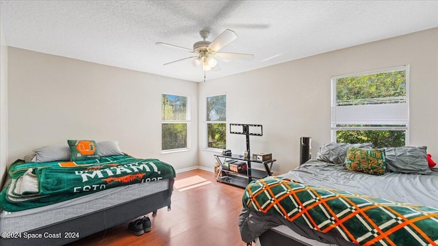 bedroom featuring ceiling fan, a textured ceiling, and wood-type flooring