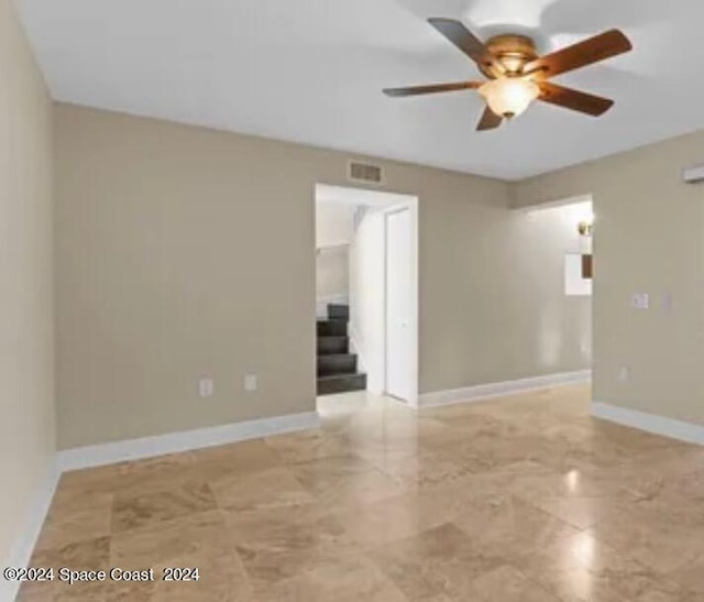 empty room with ceiling fan and light tile patterned floors