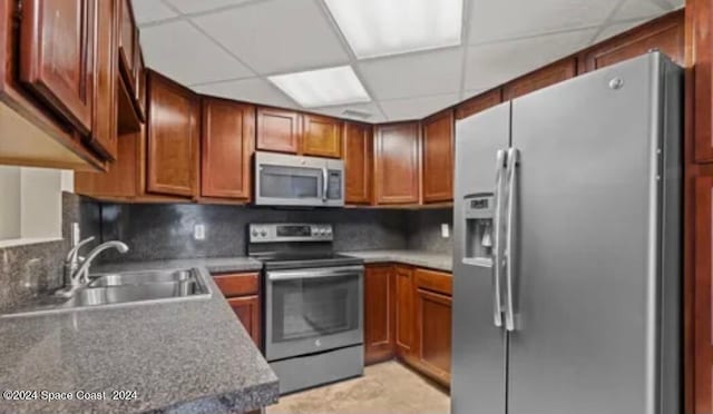 kitchen featuring appliances with stainless steel finishes, tasteful backsplash, sink, and a drop ceiling