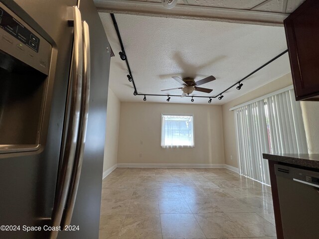 tiled empty room with rail lighting, ceiling fan, and a textured ceiling