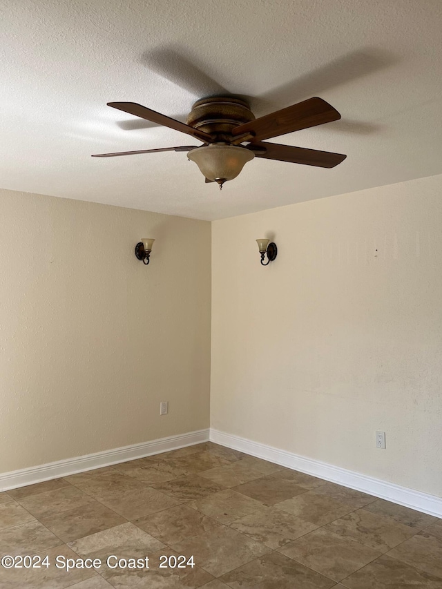 tiled spare room with a textured ceiling and ceiling fan