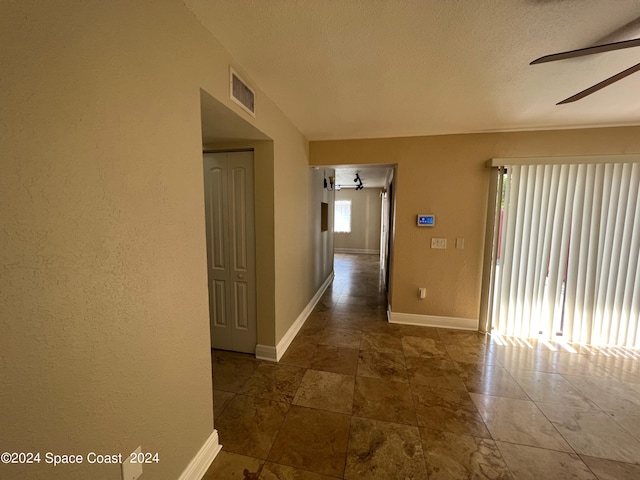 hall featuring a textured ceiling and dark tile patterned floors