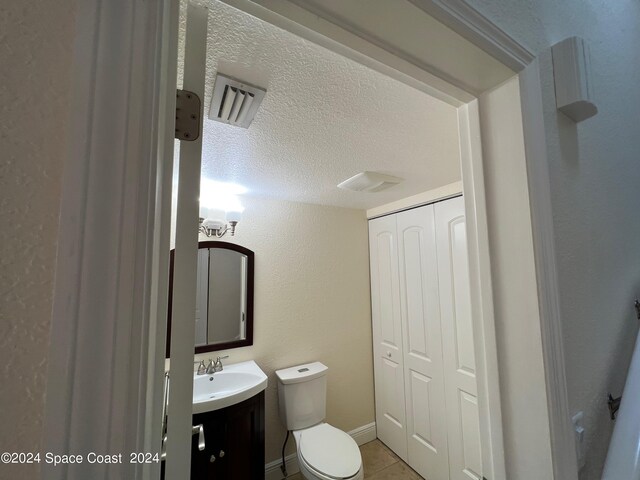 bathroom with vanity, toilet, tile patterned floors, and a textured ceiling