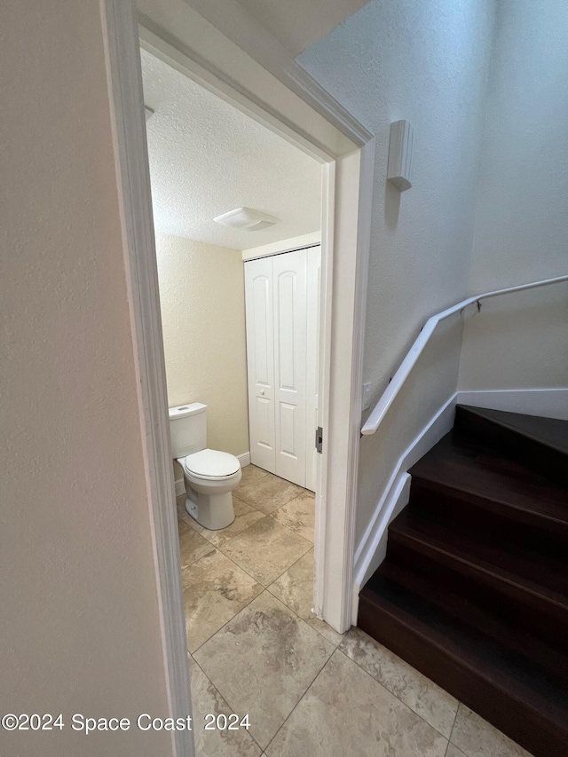 stairway featuring a textured ceiling and tile patterned flooring