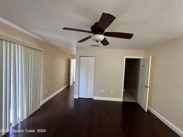 unfurnished bedroom featuring a closet, ceiling fan, dark hardwood / wood-style flooring, and a textured ceiling