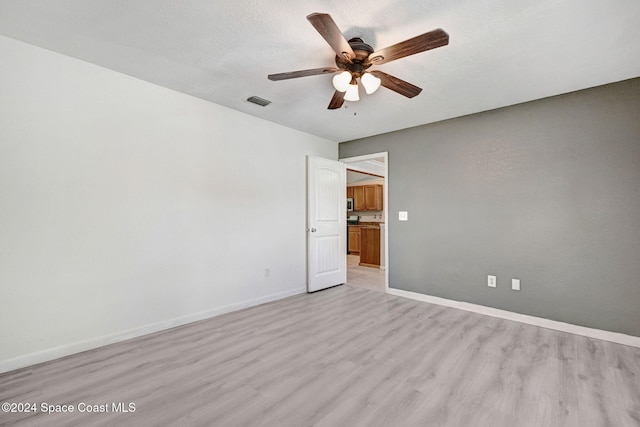 unfurnished room with a textured ceiling, ceiling fan, and light hardwood / wood-style flooring