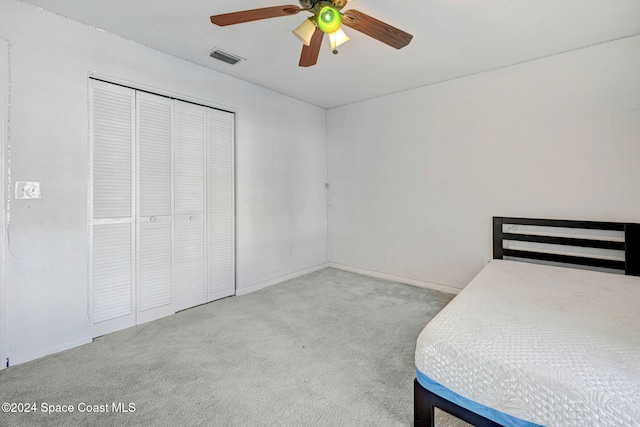 unfurnished bedroom with light carpet, ceiling fan, and a closet