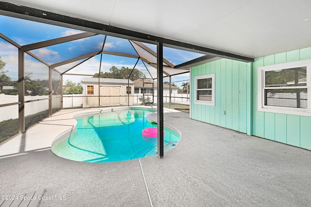 view of swimming pool with a lanai, a storage shed, and a patio area