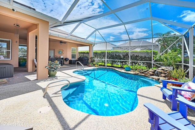 view of swimming pool featuring a grill, ceiling fan, a lanai, and a patio area