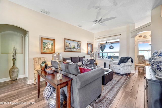 living room with ceiling fan, wood-type flooring, and a textured ceiling