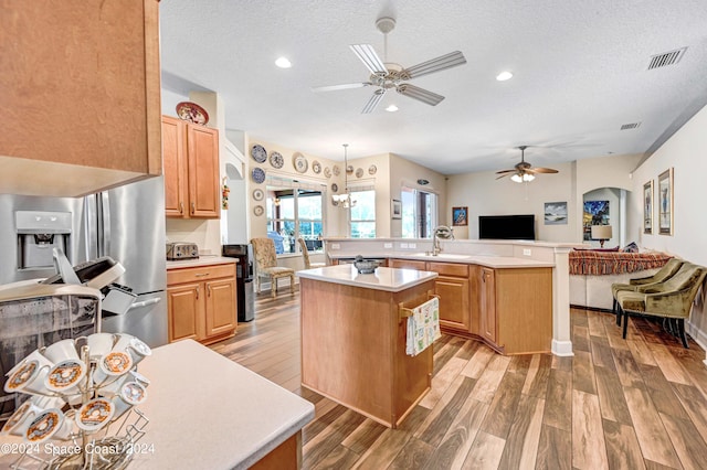 kitchen with light hardwood / wood-style flooring, a textured ceiling, stainless steel fridge, a center island, and ceiling fan