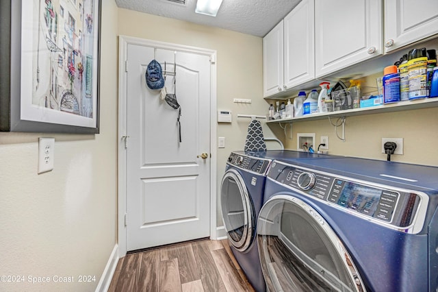 laundry area with hardwood / wood-style flooring, washer and dryer, a textured ceiling, and cabinets