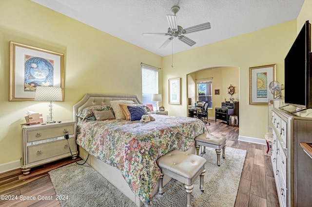 bedroom with a textured ceiling, ceiling fan, and wood-type flooring