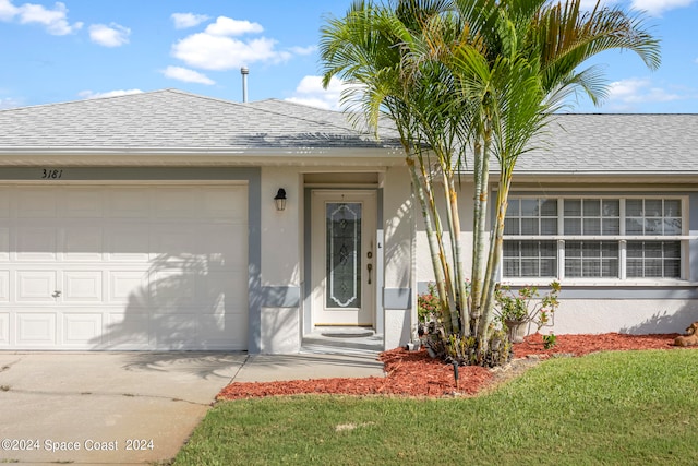 property entrance with a garage and a lawn