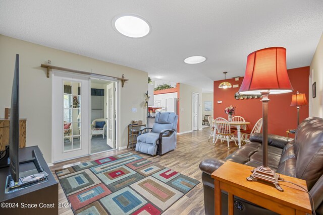 living room featuring light hardwood / wood-style floors, a wood stove, and a textured ceiling