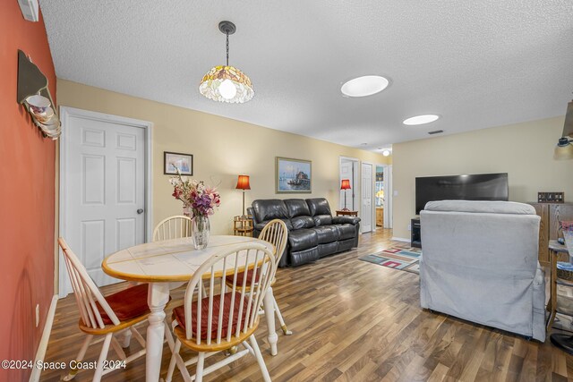 dining area featuring wood-type flooring and a textured ceiling