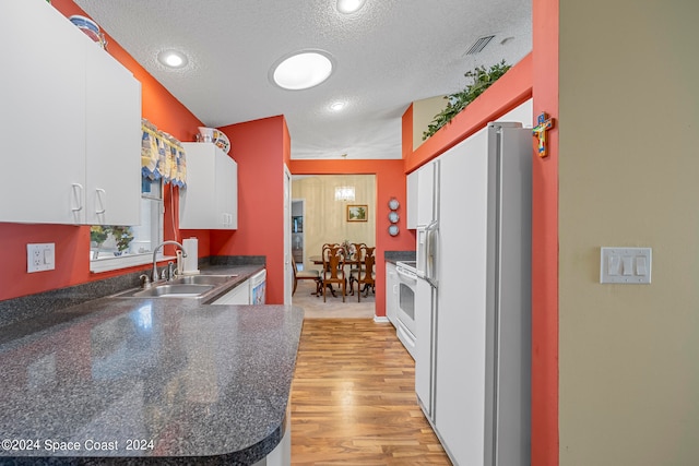 kitchen featuring sink, white refrigerator with ice dispenser, light hardwood / wood-style flooring, a textured ceiling, and white cabinetry