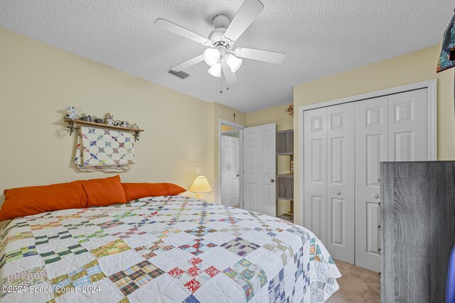 bedroom with ceiling fan, light colored carpet, a closet, and a textured ceiling