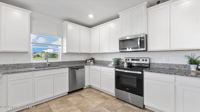 kitchen featuring white cabinetry, sink, appliances with stainless steel finishes, and dark stone counters