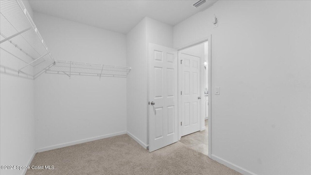 walk in closet with light carpet