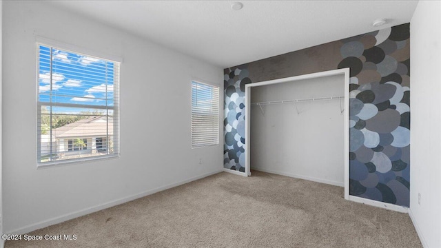 unfurnished bedroom with carpet, a closet, and multiple windows