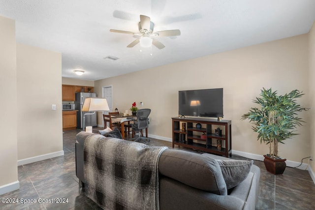 living room featuring ceiling fan and dark tile patterned flooring