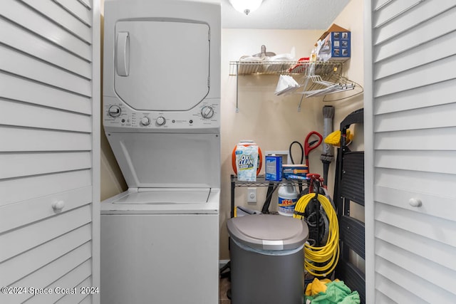 laundry area with a textured ceiling and stacked washer and clothes dryer