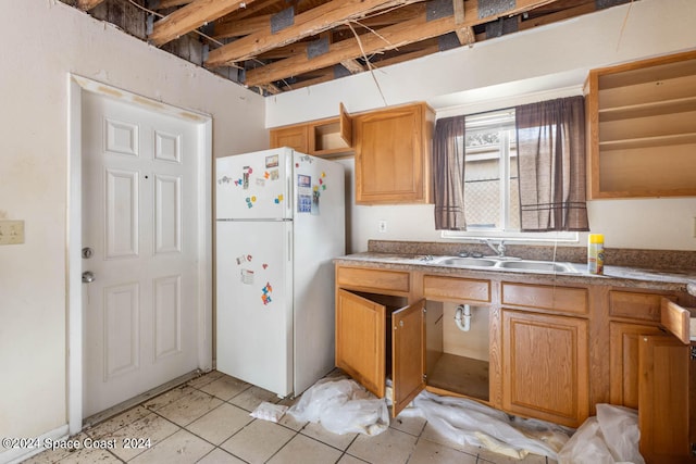 kitchen with light tile patterned floors, sink, and white fridge