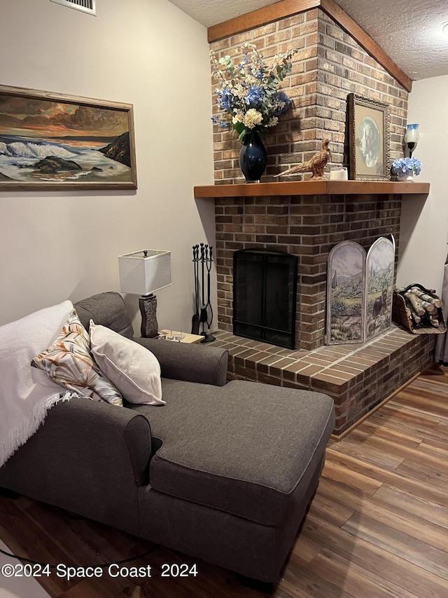 living room featuring lofted ceiling, a fireplace, hardwood / wood-style floors, and a textured ceiling