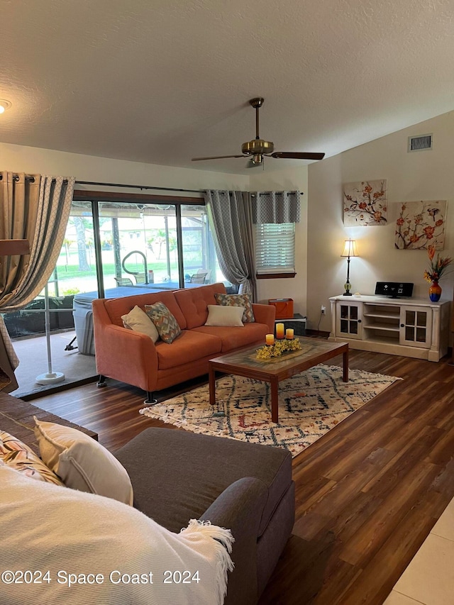 living room with dark wood-type flooring, ceiling fan, lofted ceiling, and a textured ceiling