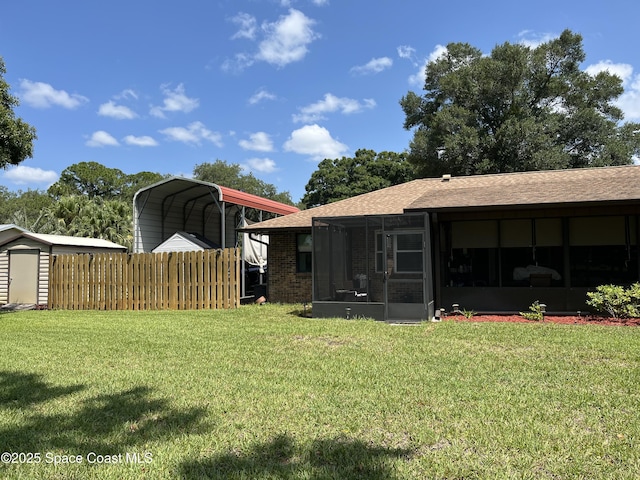 back of house featuring a carport, a sunroom, and a lawn