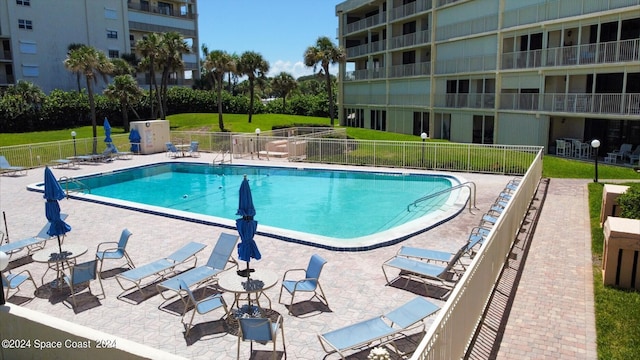 view of pool with a lawn and a patio