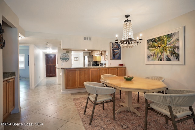 dining area featuring sink, light tile patterned floors, and a chandelier