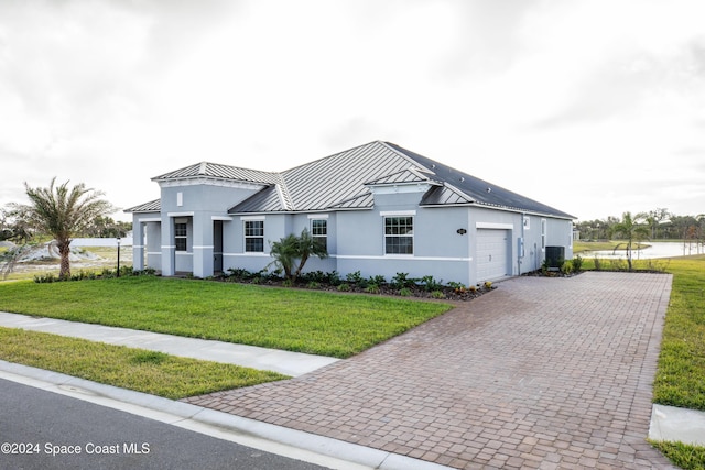 view of front facade with a garage, a water view, central air condition unit, and a front lawn