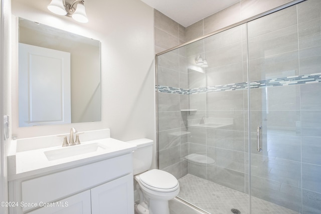 bathroom with vanity, a shower with shower door, and toilet