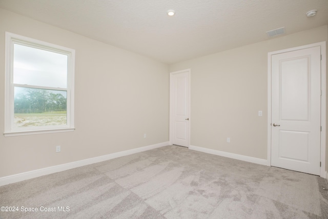 spare room with light colored carpet and a textured ceiling