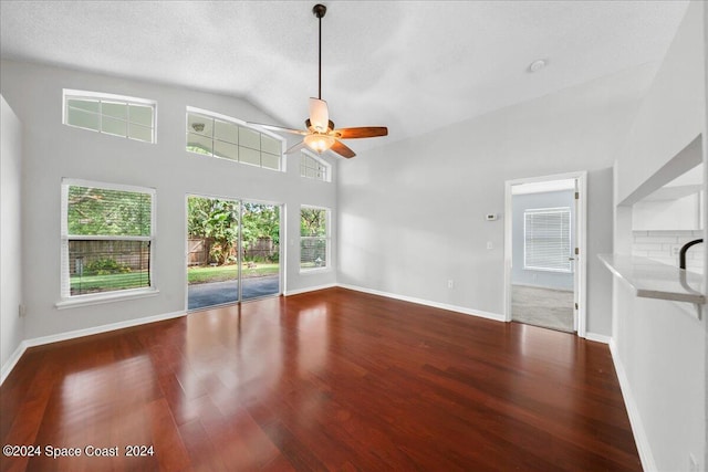 unfurnished living room featuring a textured ceiling, ceiling fan, dark wood-type flooring, and high vaulted ceiling