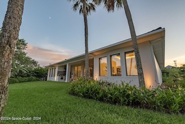 property exterior at dusk featuring a yard