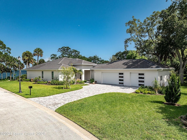 view of front of home featuring a garage, a front lawn, decorative driveway, and stucco siding