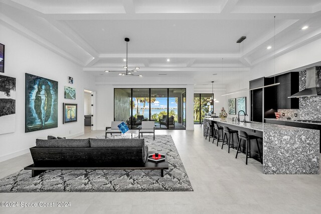 tiled living room featuring sink, a high ceiling, and coffered ceiling