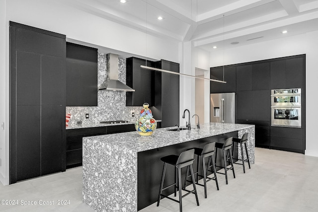 kitchen with wall chimney exhaust hood, stainless steel appliances, sink, and a spacious island