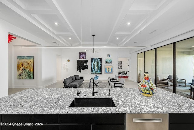 kitchen featuring sink, a large island with sink, and light stone countertops