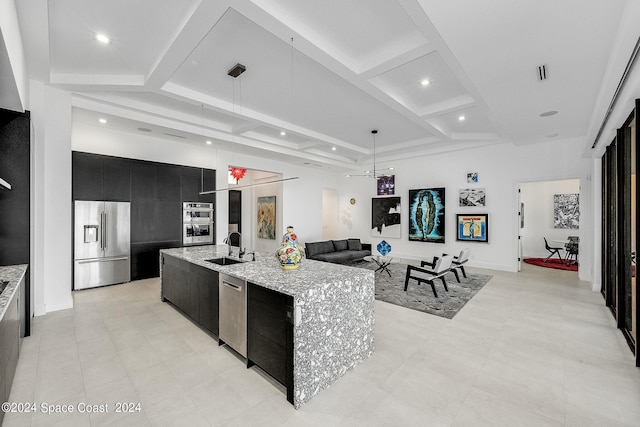 kitchen featuring a spacious island, coffered ceiling, hanging light fixtures, appliances with stainless steel finishes, and sink