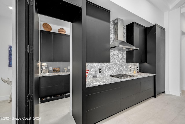 kitchen with wall chimney exhaust hood, tasteful backsplash, stainless steel gas cooktop, and light tile patterned floors